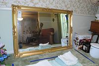 Full view of the framed decorative wall mirror showing size and gold frame with ornate detailing.