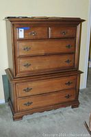 Full front view of maple wooden dresser showing 6 drawers and brass tone handles.