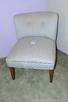 Front angled view of the light sage green sateen fabric upholstered side chair with button tufted backrest.