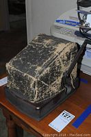 Side view of the Protectograph check writing machine with protective cover on a wooden table.