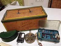 Overview of the full lot showing bait canteen box, green Old Pal tin, hand scale, sinker selector, and lure box.