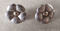Close-up front view of the pair of vintage sterling silver flower pierced earrings showing the detailed petals and smooth gold plated centers.