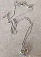 Sterling silver heart pendant attached to fine chain lying flat showing length and general condition