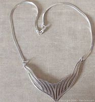 Full view of the sterling silver necklace showing the modernist pierced work centerpiece and herringbone chain.