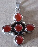 Front view of vintage sterling silver carnelian pendant showing five bezel-set cabochons arranged in a cross shape.