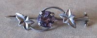 Front view of the Victorian sterling silver amethyst brooch showing detailed leaf motifs and facetted round purple stone at center.