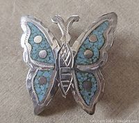 Front view of vintage sterling silver butterfly brooch pendant showing turquoise inlay.
