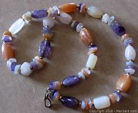 Long view of the entire vintage quartz bead necklace showing the mixture of amethyst, agate, and other quartz beads with brass spacers and a hook closure.