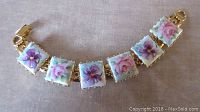 Full view of the porcelain floral link bracelet showing gold-tone setting and six hand-painted square links depicting flowers.