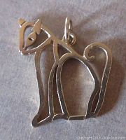 Photo showing front side of open work 14K yellow gold cat pendant with stylized modernist design features including eyes, ears, legs, and curled tail.
