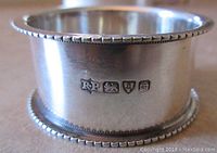 Close-up of British hallmarks on the sterling silver napkin ring showing maker's mark and assay marks.