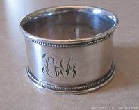 Side view of sterling silver napkin ring showing monogram 'EAH' with beaded edges