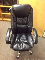 Front view of black leather office chair showing padded backrest, seat, and armrests.