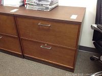 Front view of wooden two drawer filing cabinet with metal handles showing general condition and key locks without keys.
