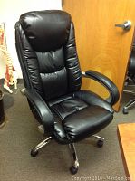 Front view of black padded office chair with wheels, padded armrests, and adjustable height.