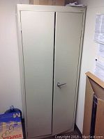 Front view of beige metal filing cabinet with two doors and right-side handle.