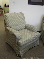 Full view of the armchair showing overall shape, cushioning, and slipcover pattern in green fabric with diamond motifs.