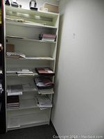 Full view of tall white bookshelf with 7 shelves, containing papers and folders.