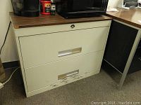 Large metal filing cabinet front view showing three drawers with horizontal handles and scratches on lower drawer.
