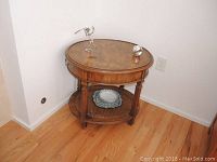 Angle showing round wooden end table with cane woven bottom shelf and decorative legs