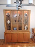 Front view of the Bernhardt lighted china cabinet showing upper glass display doors with lighting and lower wood storage cabinets. Assorted dishes inside not included.