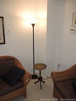 Torchiere floor lamp beside wicker chair with side table, showing lamp height and overall set