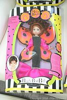 Front view of Madame Butterfly doll in unopened box with pink butterfly wings and black and pink outfit.