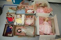 Eight vintage Madame Alexander dolls in original boxes surrounded by tissue paper, various dresses and sizes