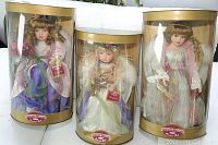 Three Bonnie Memories porcelain dolls, each in original cylindrical packaging with clear front, sitting side by side.