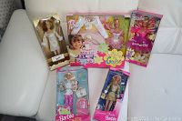 Set of five Barbie dolls in original packaging on white surface.
