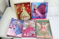 Wide shot showing all five Barbie dolls in original packaging arranged together on a white surface.