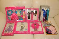 Full lot display showing boxed and loose Barbie clothing items arranged on a couch including the Gift Pack, multiple Fashion Avenue International outfits, and a small tray of assorted clothes and shoes.
