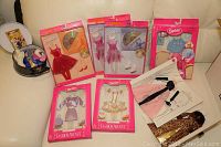Photo showing multiple boxed Barbie Fashion Avenue outfits and a carry case with additional doll clothes.