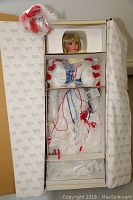Full view of Rustie porcelain doll Liberty 'Breather' in original box showing doll dressed in red, white and blue costume with protective foam.