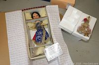 Photo of boxed porcelain doll with protective padding and certificate of authenticity visible