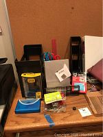 Desk organizer holding scissors, pens, ruler, and other office supplies arranged on a wooden desk surface with cork memo board backdrop.