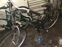 Two Giant Boulder SE bicycles with green frames, flat tires, and rusted brake lines parked indoors.