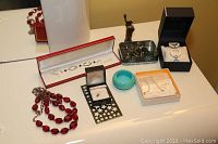 Full assortment of costume jewelry on table including bead necklaces, bangle, watch, earring boxes