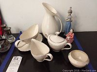 Overview of four Lenox china pieces and two Lladro figurines on display.