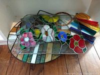 Eight stained glass pieces including floral and geometric designs alongside a multicolored windchime