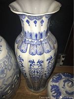 Front view of tall scalloped-rim blue and white vase showing floral motifs