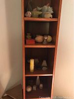 Wooden shelf with four levels displaying various marble and stone decorative statues and collectible rock formations in assorted shapes and colors.