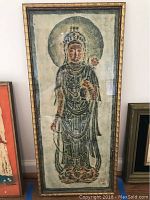 Front view of the framed Thailand hand rubbing wall art depicting a standing figure with a halo and detailed attire.