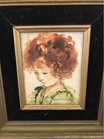 Front view of the watercolor portrait painting of a red headed girl framed in a primitive style gold and black frame with artist signature visible.