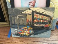 Painting of flower stall showing colorful flowers in front, signed E. Kiven
