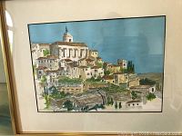 Full view of one framed watercolor painting by Frank Sprink showing a Mediterranean village and church under a blue sky.