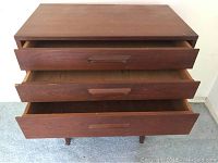 Top view showing three drawers pulled open on one wooden chest of drawers.