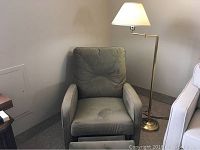 Front view of electric recliner and brass reading lamp in corner of room, showing recliner's cushion and fabric texture