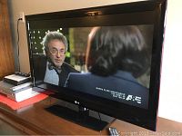 Front view of television powered on, seated on pedestal stand