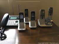 Two cordless phone systems including Vtech base and handsets, Panasonic base and handsets arranged side by side.